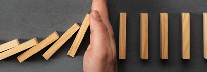 Hand stopping dominoes from cascading